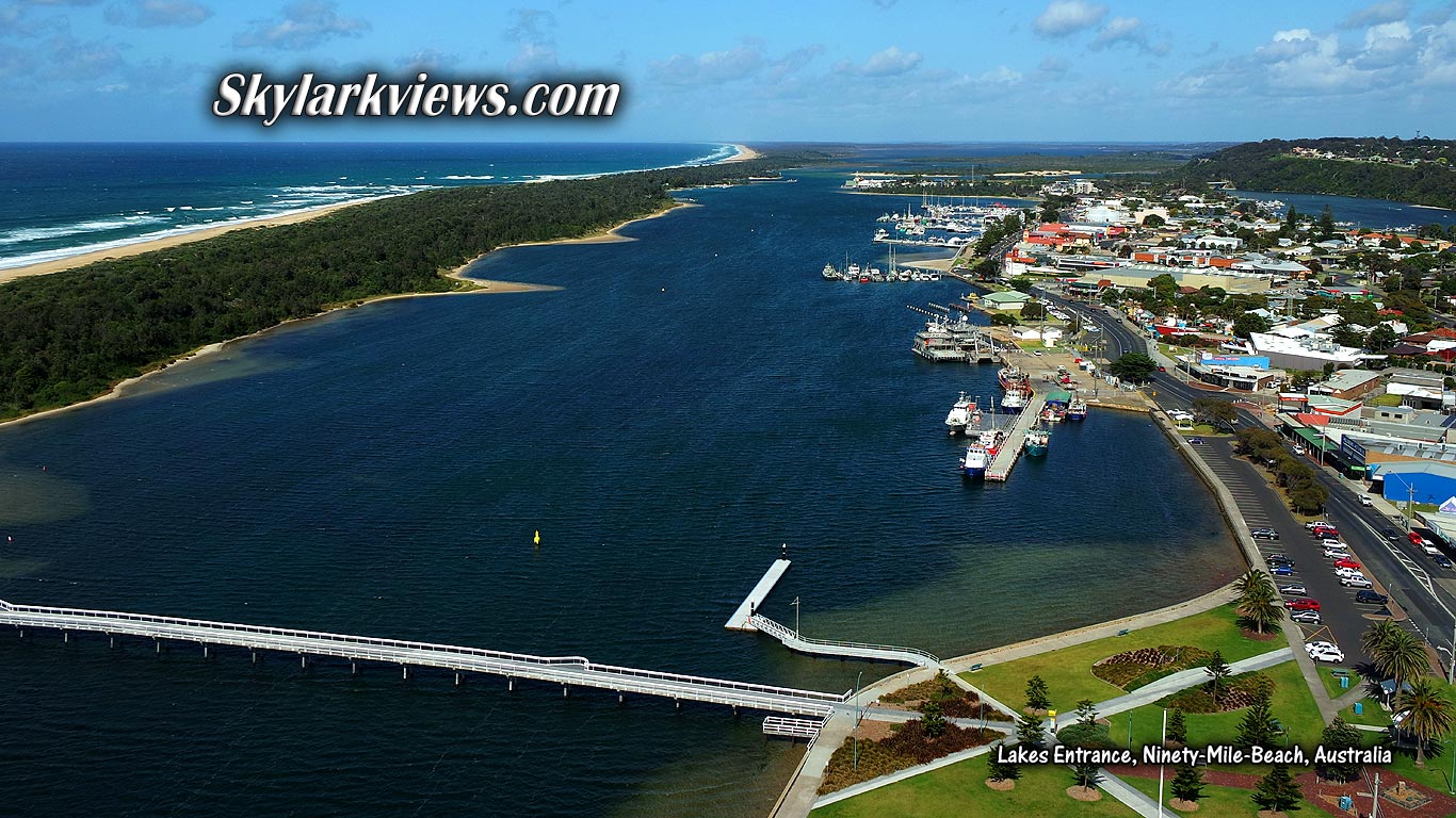 aerial view of bridge crossing a lake; boats, beach and ocean